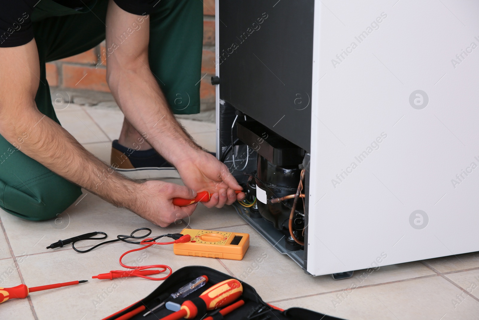 Photo of Male technician repairing broken refrigerator indoors, closeup