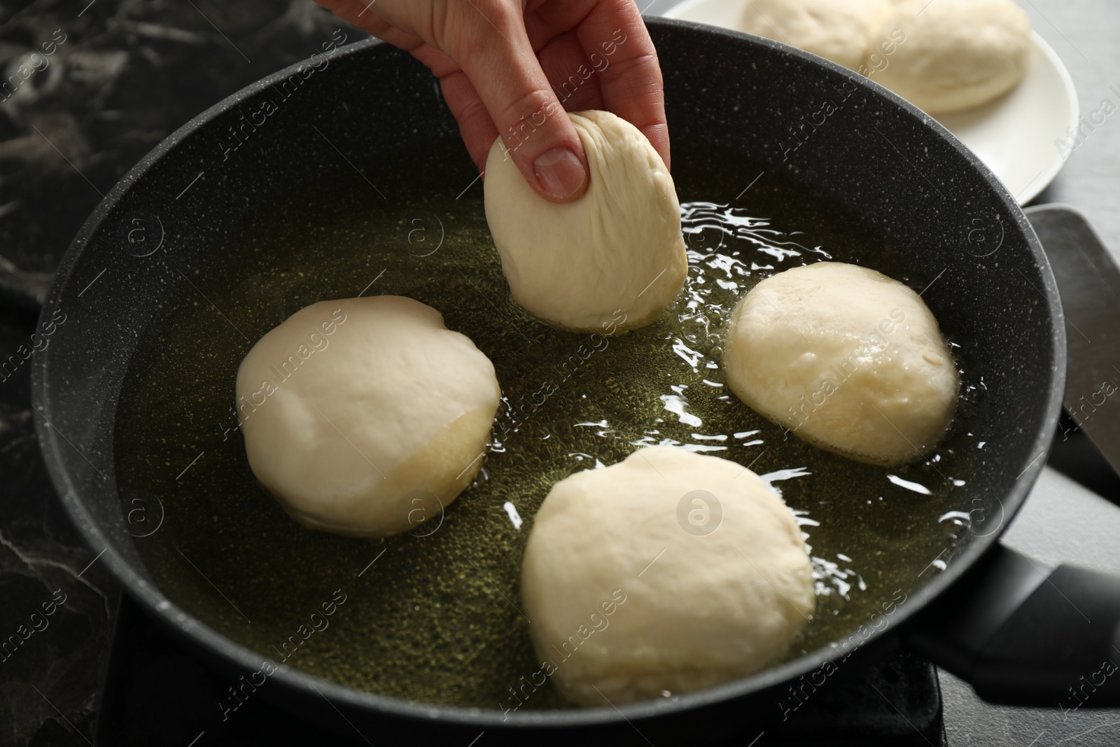 Photo of Woman cooking delicious donuts in oil, closeup