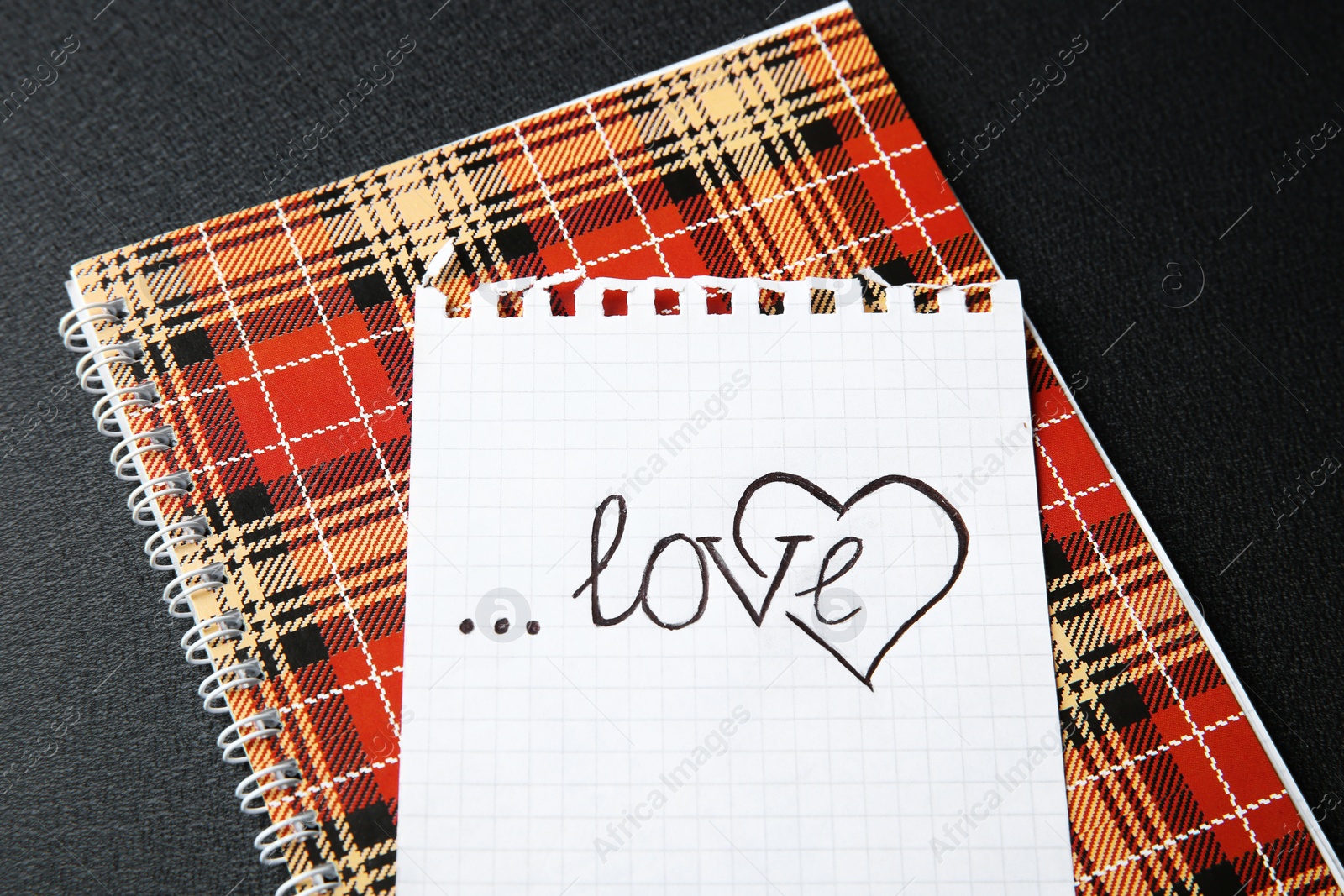 Photo of Notebook and paper with word LOVE on dark background