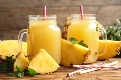 Photo of Delicious pineapple juice and fresh fruit on wooden table