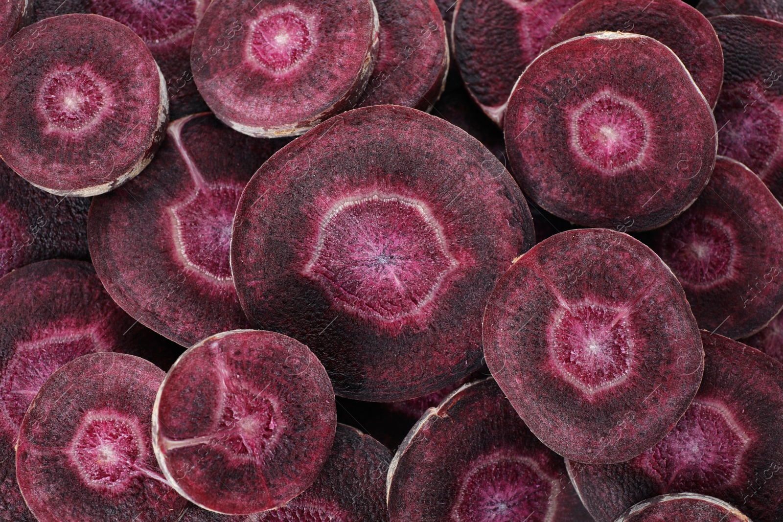 Photo of Slices of raw purple carrot as background, closeup