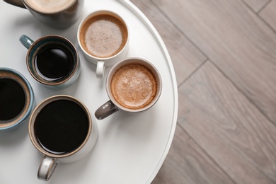 Photo of Many cups of different aromatic hot coffee on table, top view