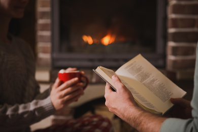 Photo of Couple reading book together near fireplace, closeup