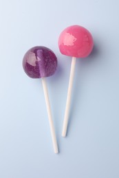 Photo of Tasty lollipops on light blue background, flat lay