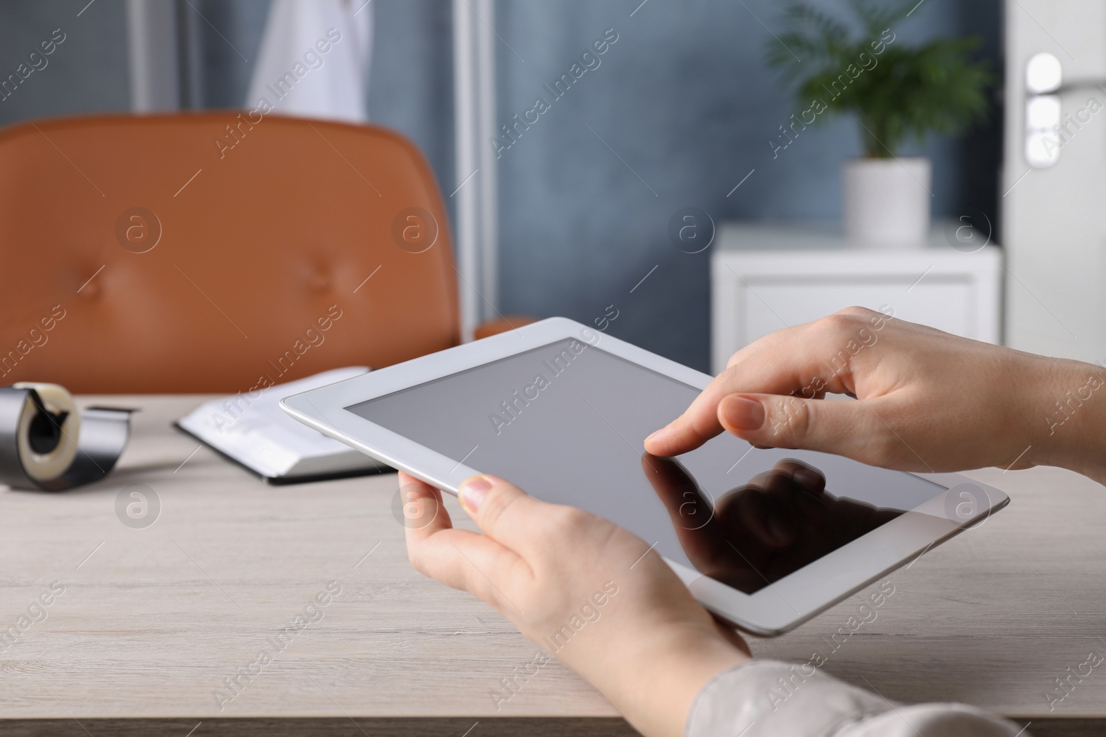 Photo of Woman using modern tablet at workplace indoors, closeup