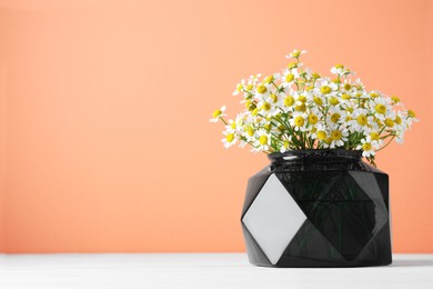 Photo of Vase with beautiful chamomile flowers on white wooden table. Space for text