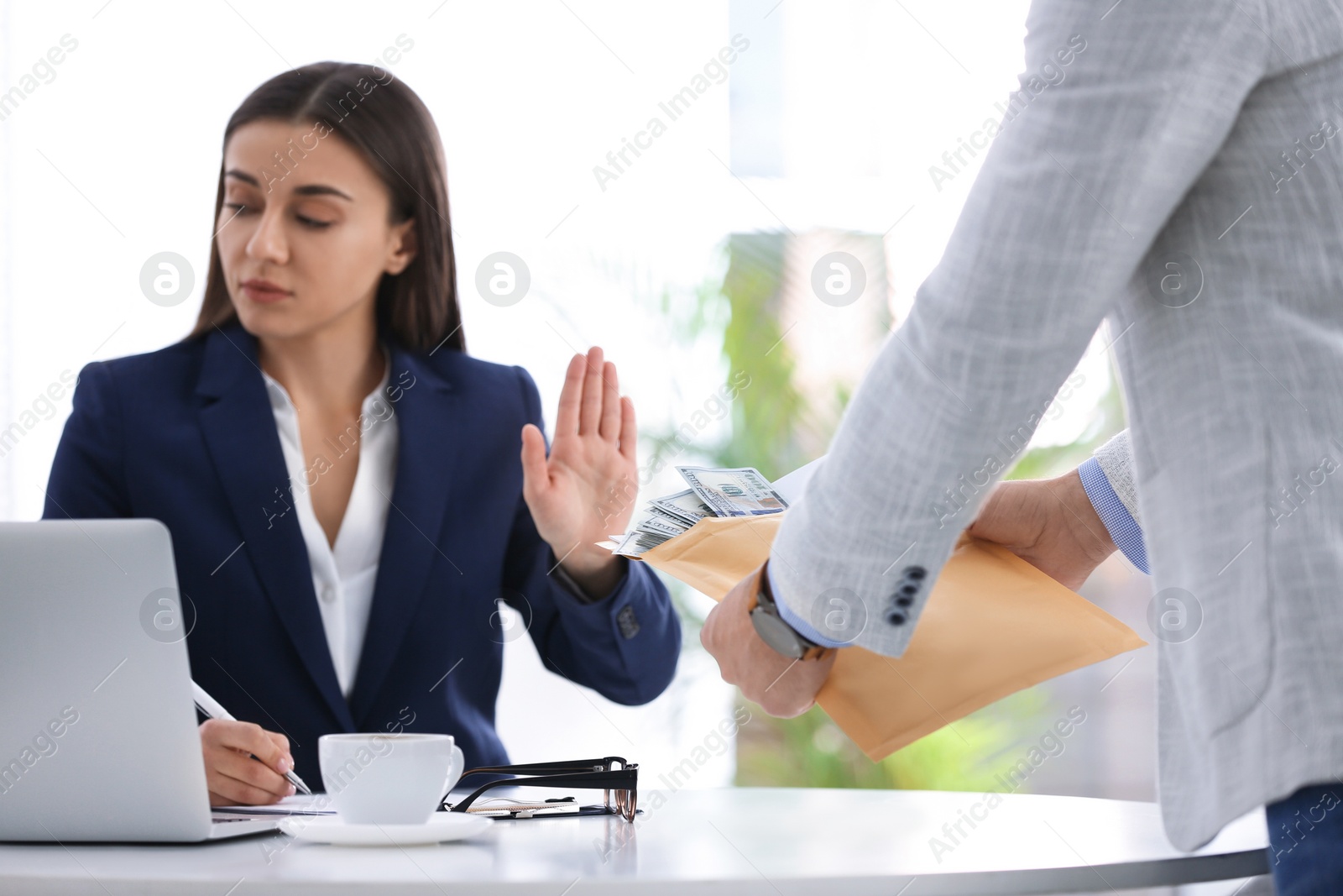 Photo of Businesswoman rejecting bribe at table in office