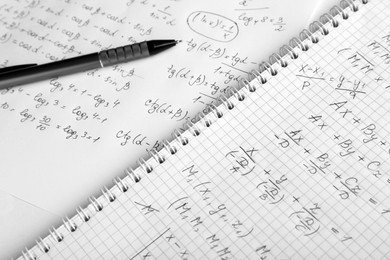Photo of Paper with different mathematical formulas and pen, closeup