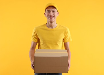 Photo of Happy courier with parcel on orange background