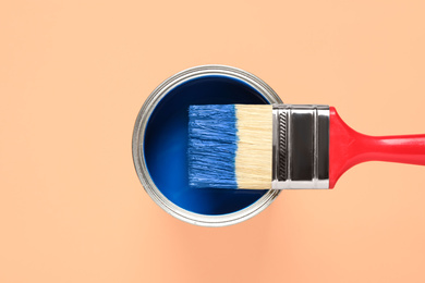 Photo of Can of paint and brush on orange background, top view. Color of the year 2020 (Classic blue)