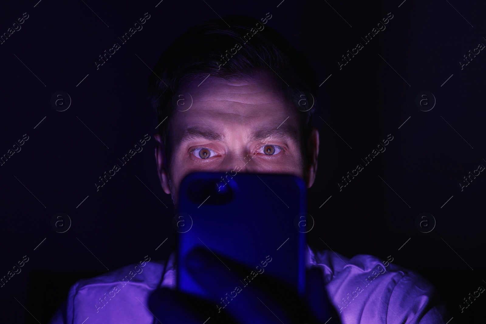 Photo of Man using smartphone at night, closeup. Internet addiction