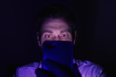 Man using smartphone at night, closeup. Internet addiction