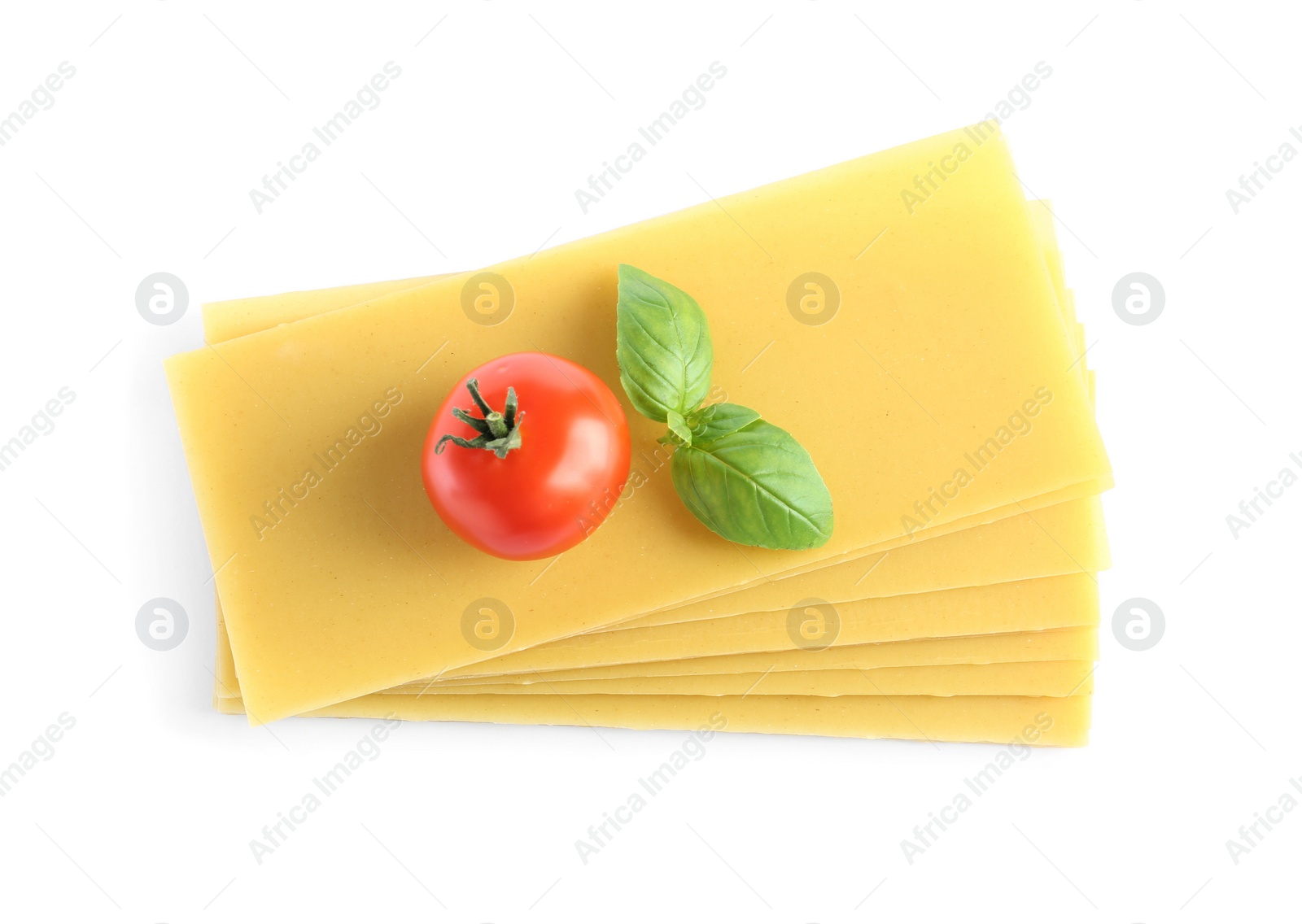 Photo of Uncooked lasagna sheets, tomato and basil on white background, top view