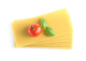 Photo of Uncooked lasagna sheets, tomato and basil on white background, top view