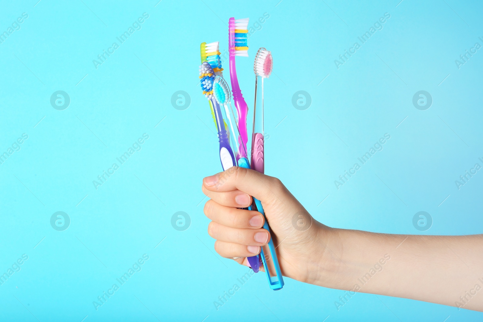 Photo of Woman holding manual toothbrushes against color background