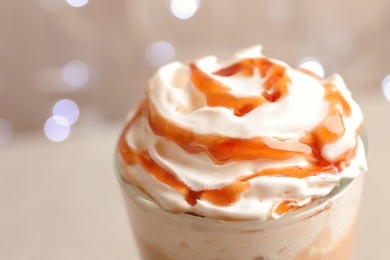 Glass with delicious caramel frappe on blurred background, closeup