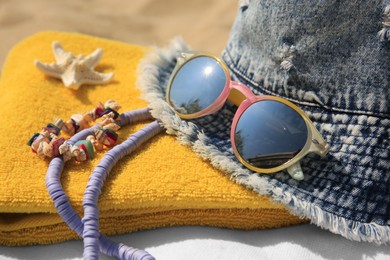 Denim hat and beach accessories on sand, closeup