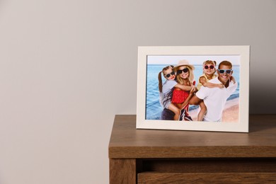 Frame with family photo on wooden chest of drawers, space for text