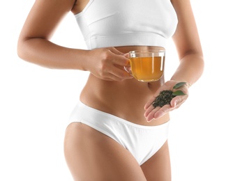 Young woman with fresh and dry leaves holding cup of diet tea on white background, closeup