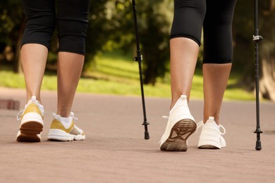 Photo of Two friends performing Nordic walking outdoors, closeup