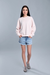 Photo of Full length portrait of young woman in sweater on grey background. Mock up for design