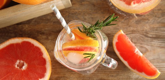 Flat lay composition with mason jar of infused water and grapefruit slices on wooden table. Banner design