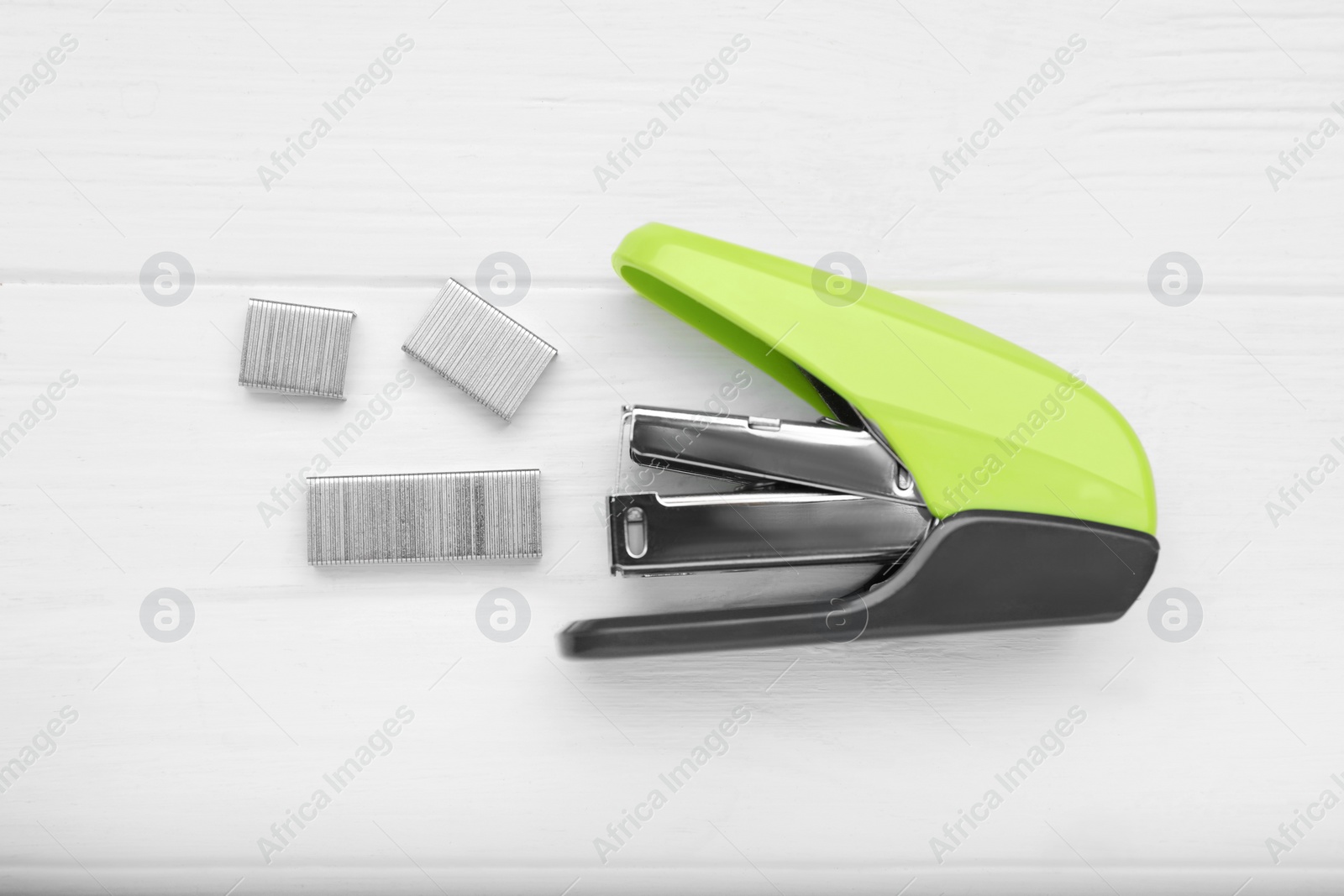 Photo of New bright stapler on white wooden table, flat lay. School stationery