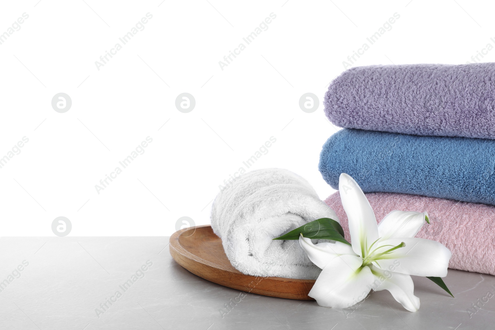 Photo of Fresh towels and lily flower on light grey marble table against white background. Space for text