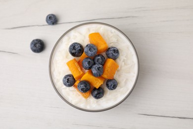 Photo of Bowl of delicious rice porridge with blueberries and pumpkin on white table, top view