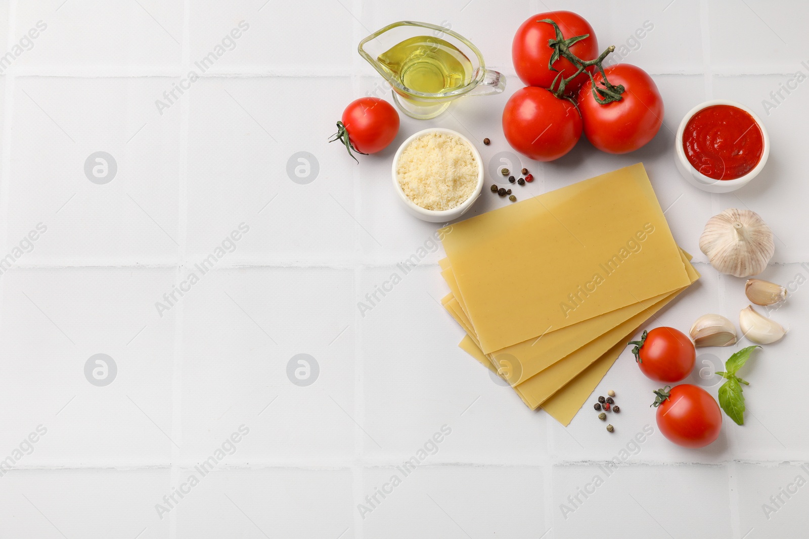 Photo of Ingredients for lasagna on white tiled table, flat lay. Space for text