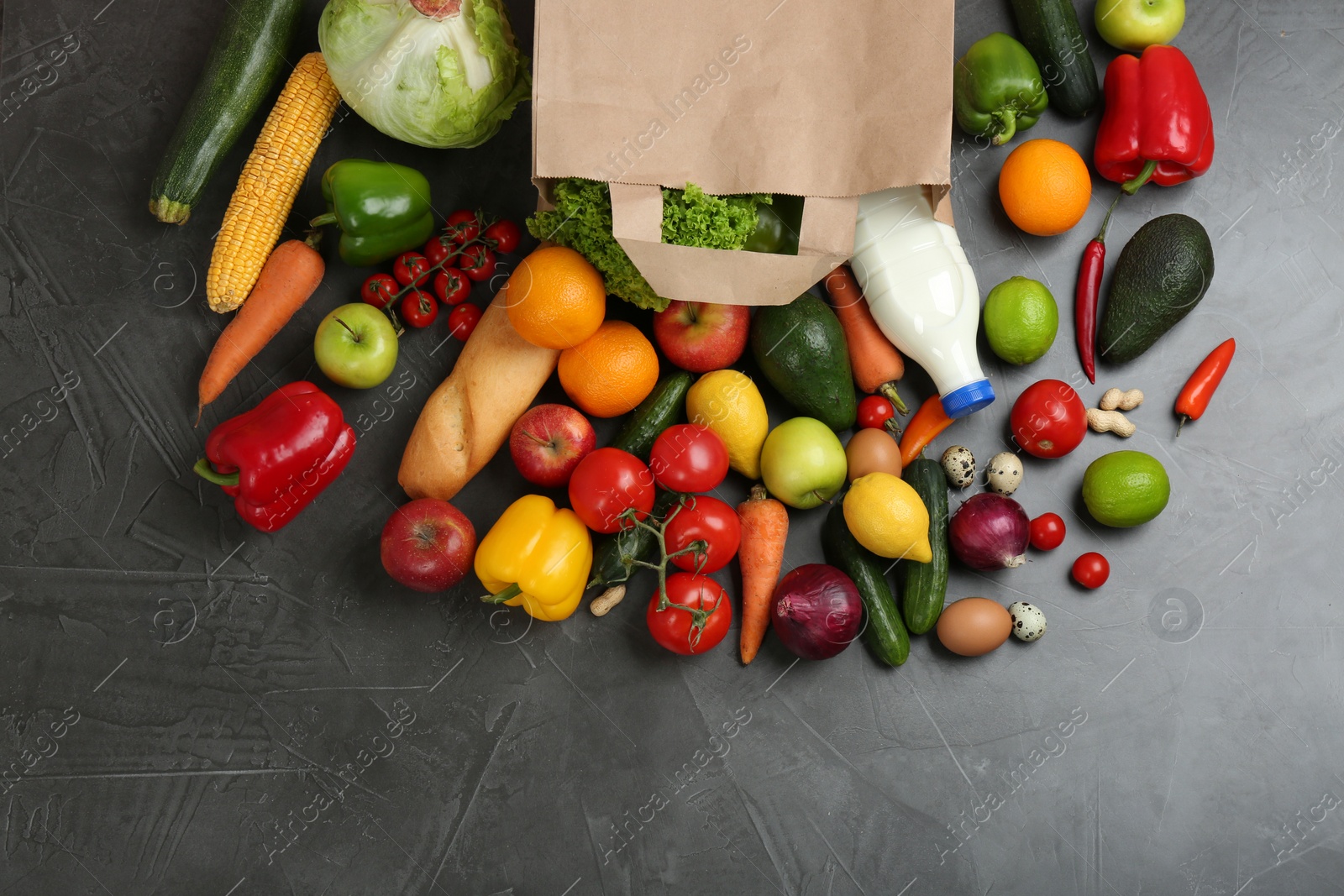 Photo of Flat lay composition with overturned paper bag and groceries on grey table