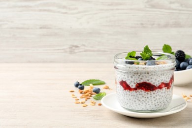 Delicious chia pudding with berries and granola on wooden table. Space for text