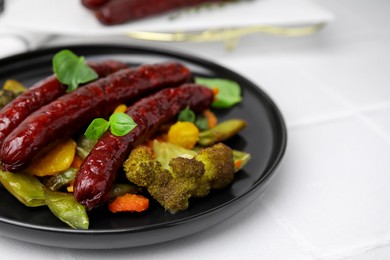 Photo of Delicious smoked sausages and baked vegetables on light table, closeup
