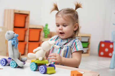 Photo of Little girl playing with toys at table