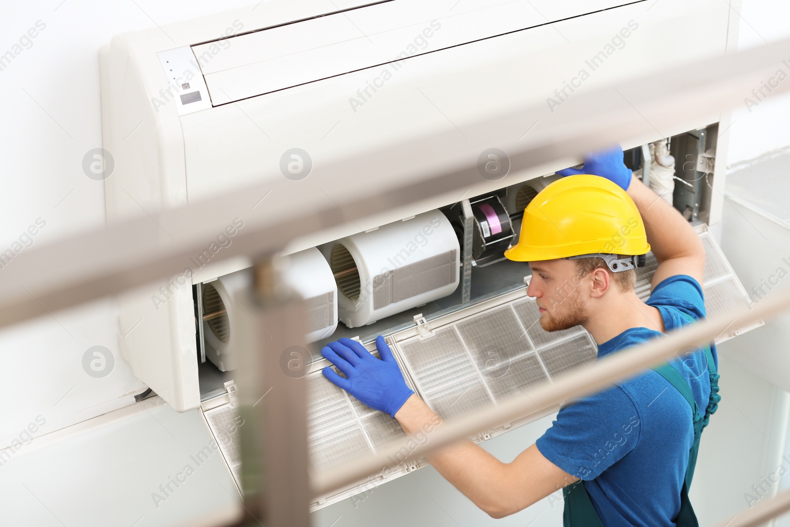 Photo of Professional technician maintaining modern air conditioner indoors