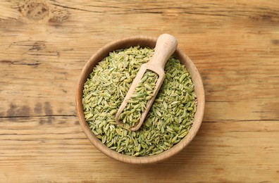 Photo of Bowl and scoop with fennel seeds on wooden table, top view