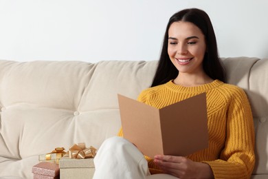 Happy woman reading greeting card on sofa in living room