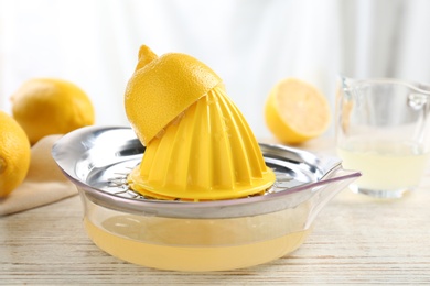 Plastic citrus juicer with lemon half on wooden table