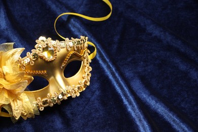 Photo of Theater arts. Golden venetian carnival mask on blue fabric, closeup. Space for text