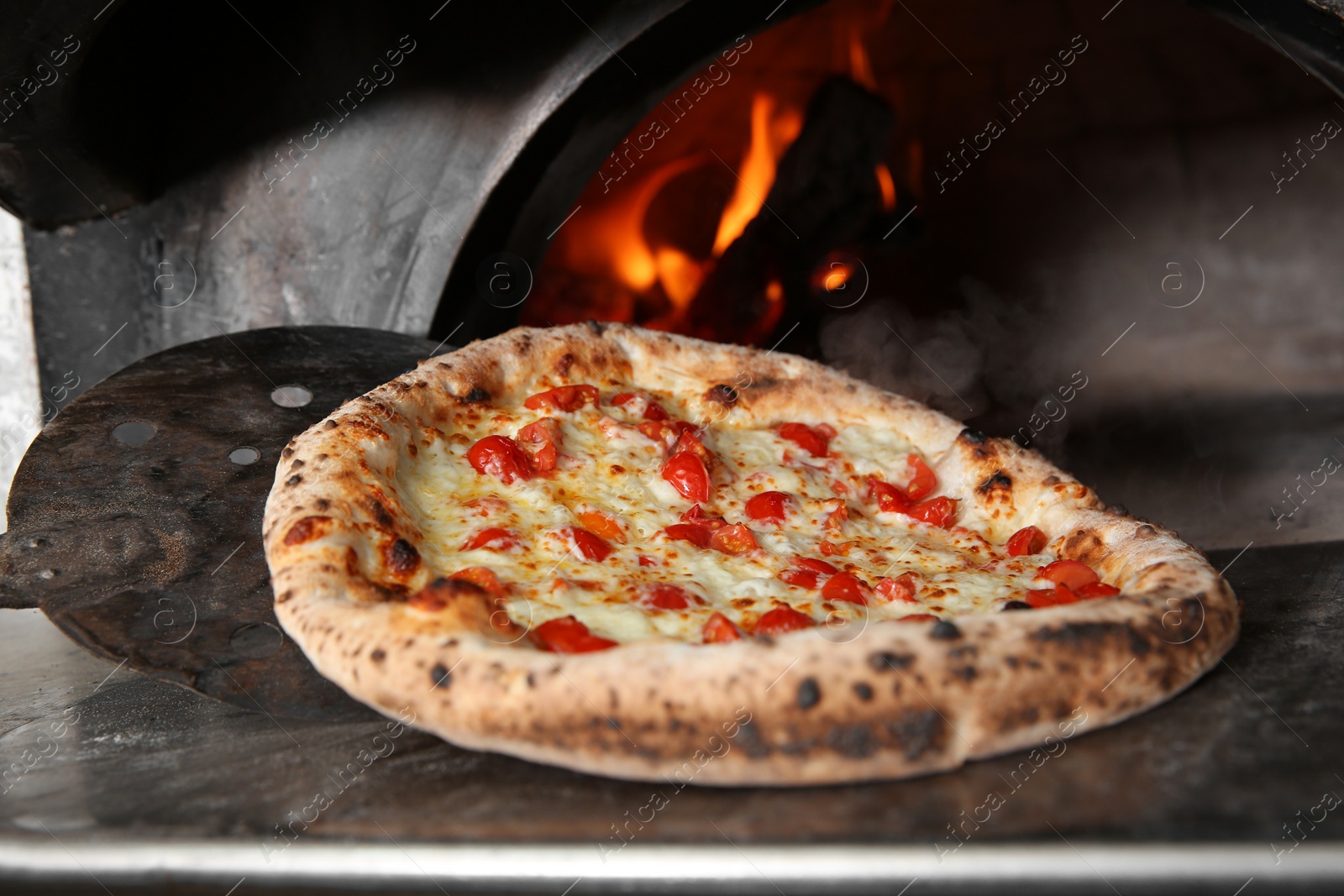 Photo of Taking out tasty pizza from oven in restaurant kitchen