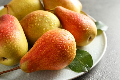 Photo of Plate with ripe pears on grey background, closeup