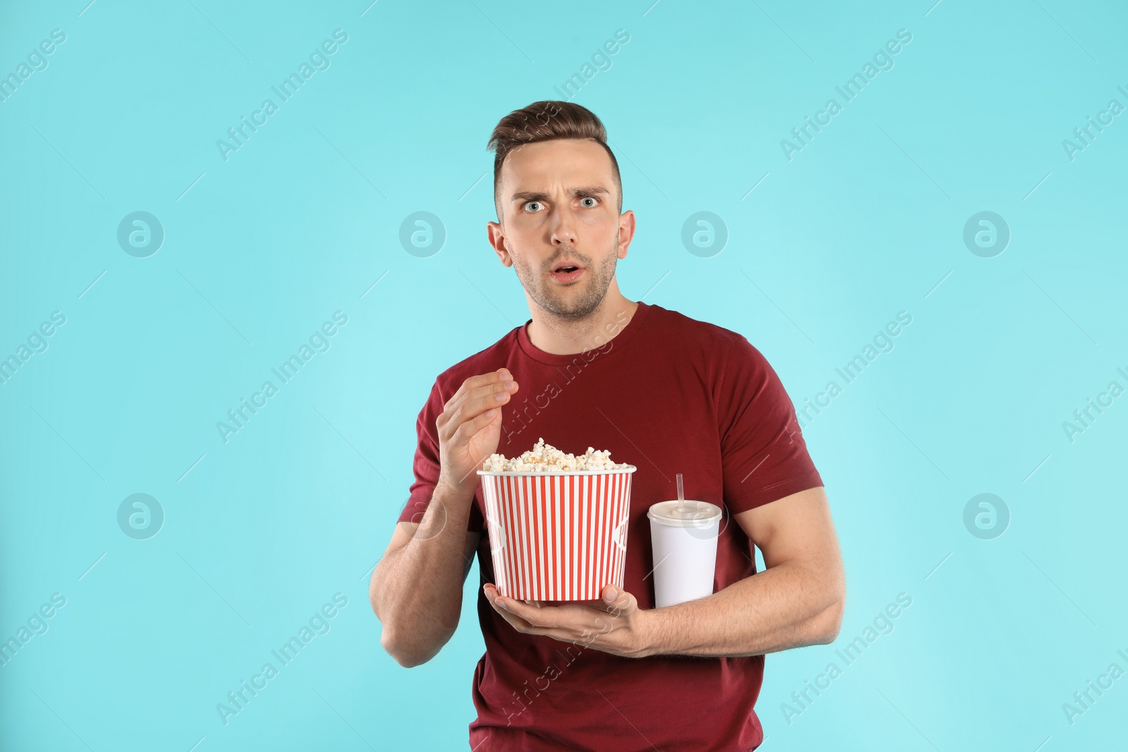 Photo of Emotional man with popcorn and beverage during cinema show on color background