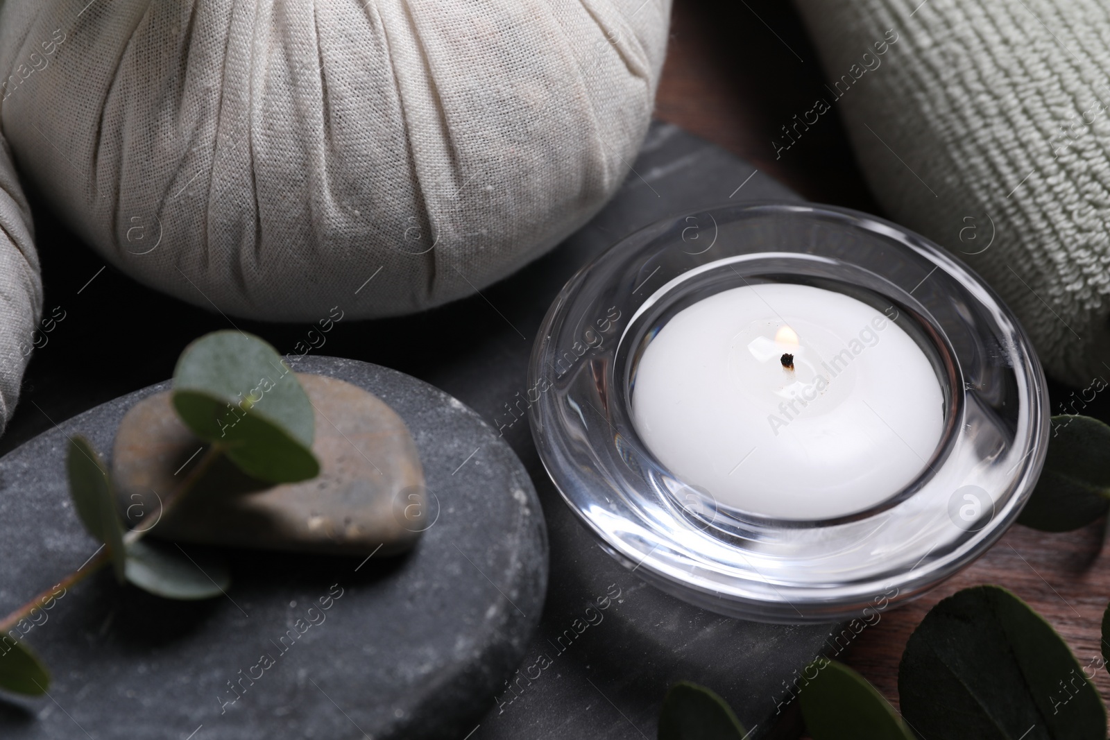 Photo of Beautiful spa composition with herbal massage bags, stones and eucalyptus branches on wooden table, closeup