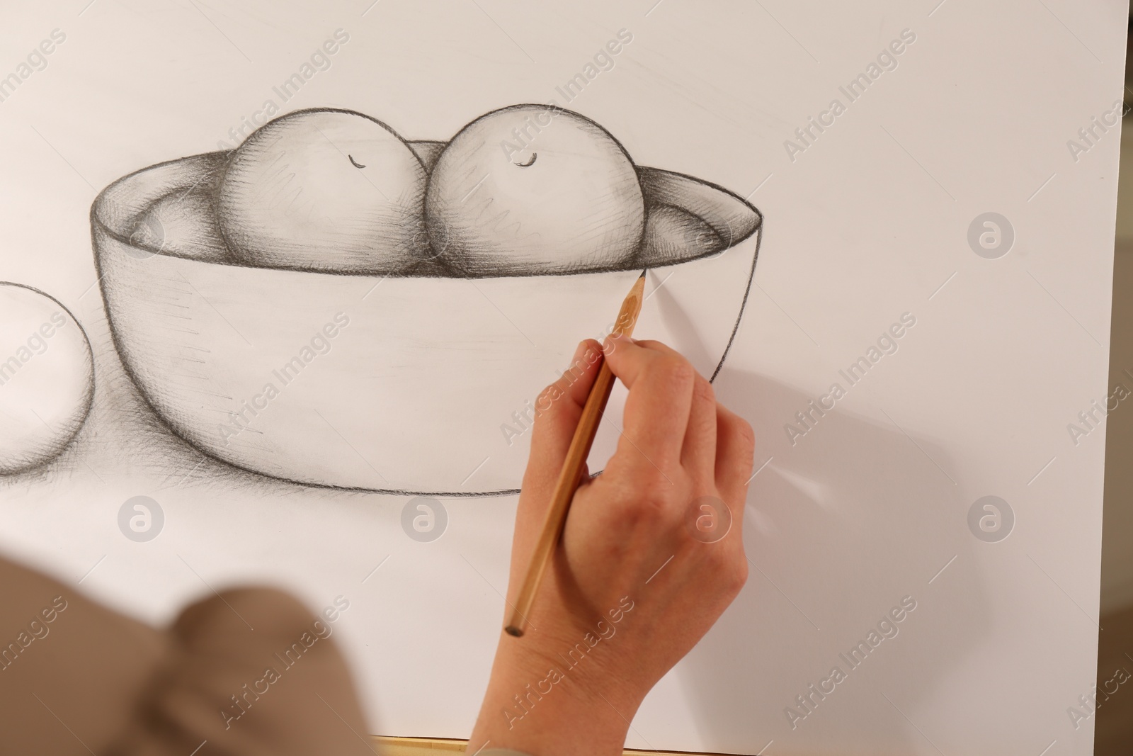 Photo of Woman drawing bowl of fruits with graphite pencil on canvas, closeup