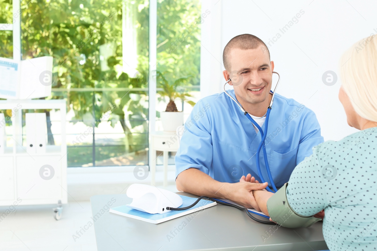 Photo of Male medical assistant measuring female patient blood pressure in clinic