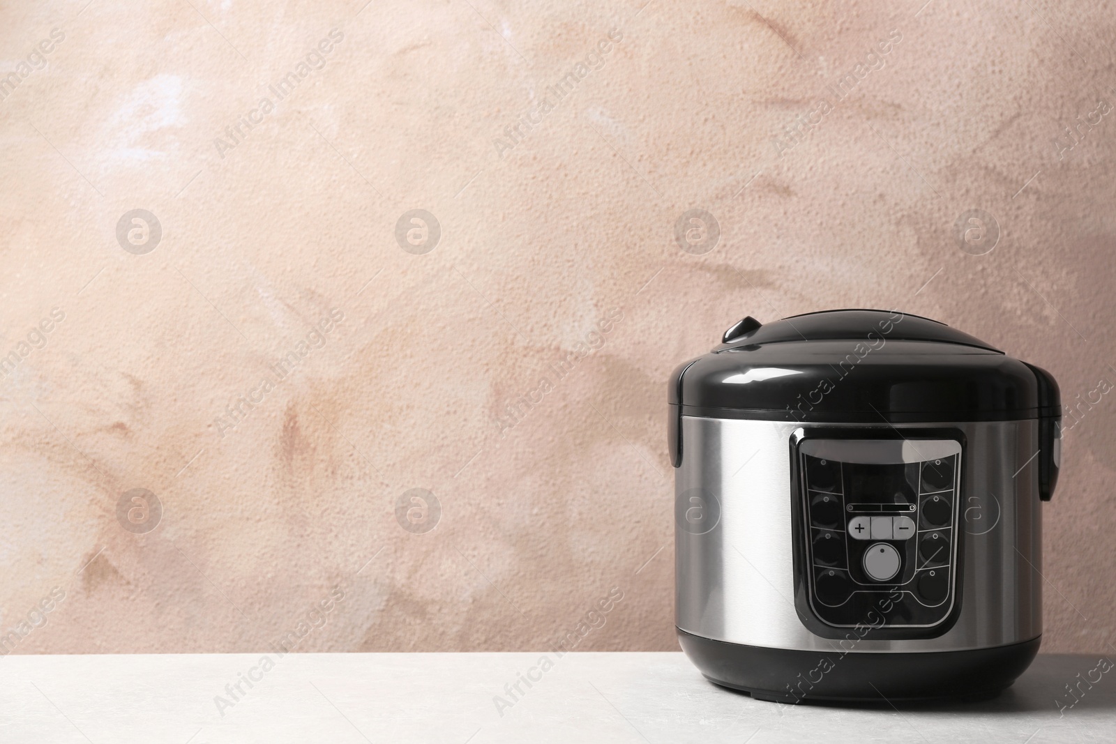 Photo of Modern multi cooker on table against color wall. Space for text