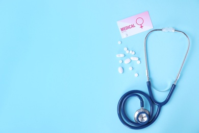 Photo of Flat lay composition with stethoscope and pills on blue background, space for text. Gynecology concept