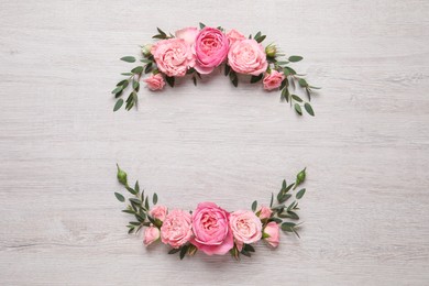 Photo of Wreath made of beautiful rose flowers and green leaves on white wooden background, flat lay. Space for text