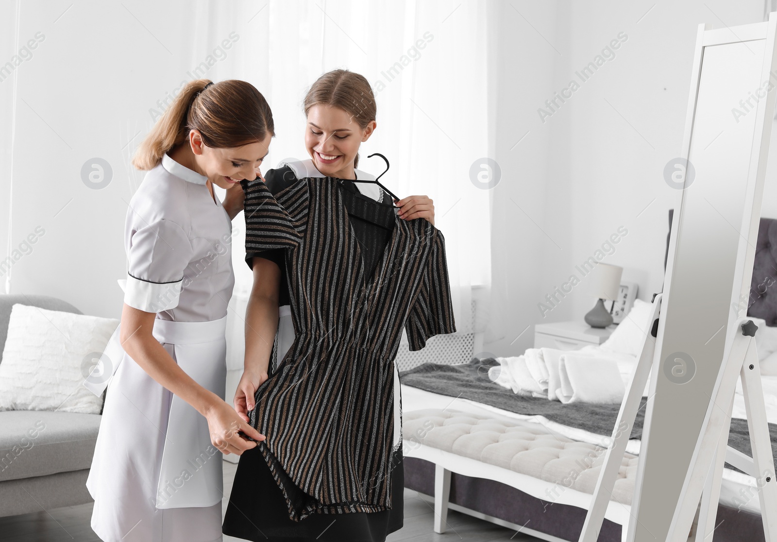 Photo of Young chambermaids trying on clothes in hotel room