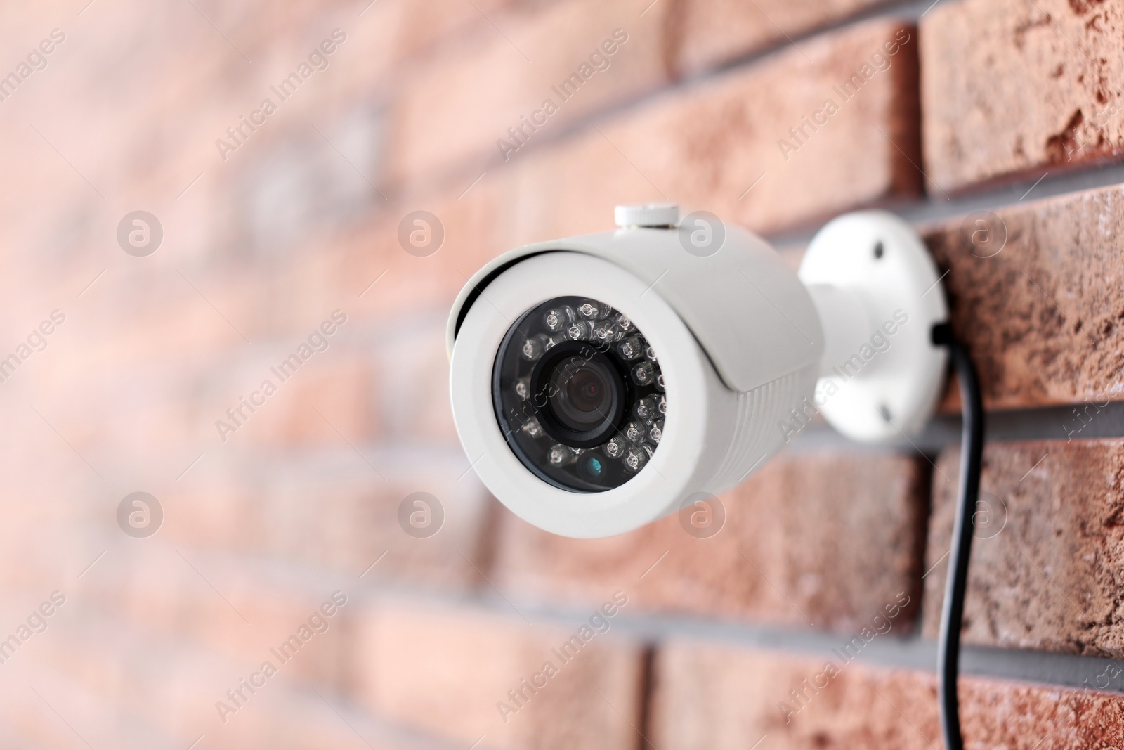 Photo of Modern security CCTV camera on brick wall